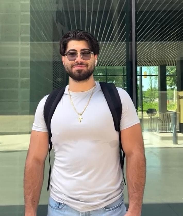 Student smiling outside a glass campus building