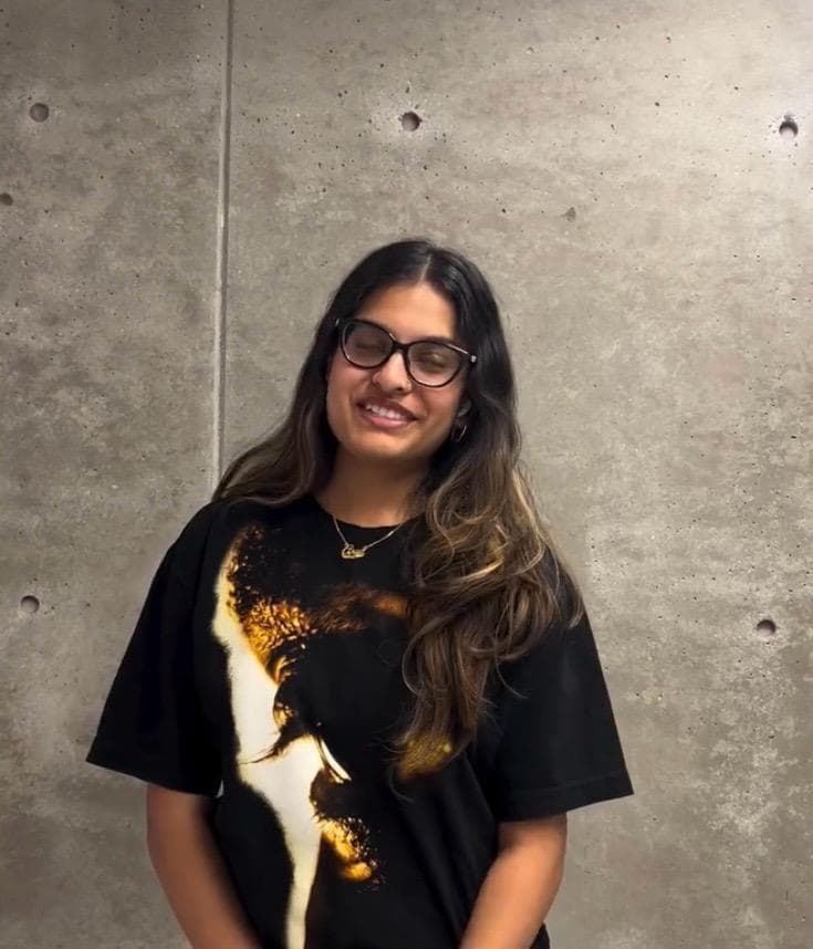 Student smiling against a concrete campus wall